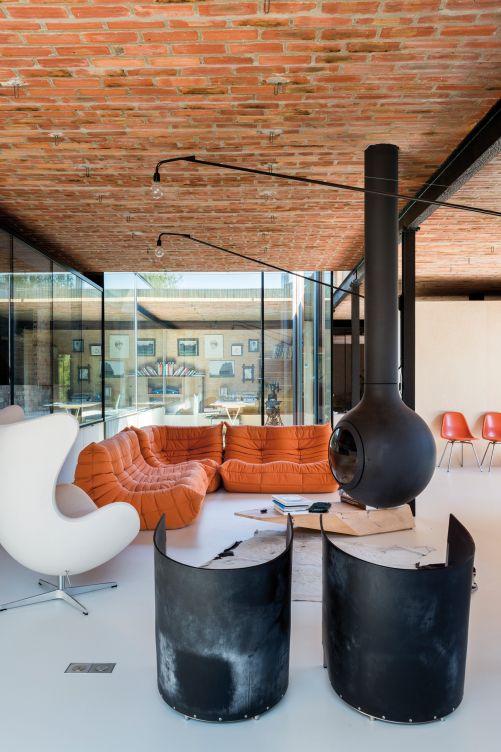 Das überschaubare Interieur betont die besondere Architektur aus Backstein und Glas: Sofa «Togo» von Michael Ducaroy für Ligne Roset, Sessel «Eggchair» von Arne Jacobsen für Fritz Hansen, Fauteuil «S88» von Maarten Van Severen für Lensvelt.