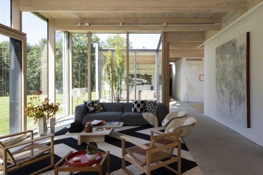 Dank der Verglasung wirkt die Wiese als optische Erweiterung des Wohnbereichs bis hin zum Waldrand. Die Vintage-Möbel harmonieren mit dem neuen Sofa von Montis und den Accessoires von Comerford Collection.