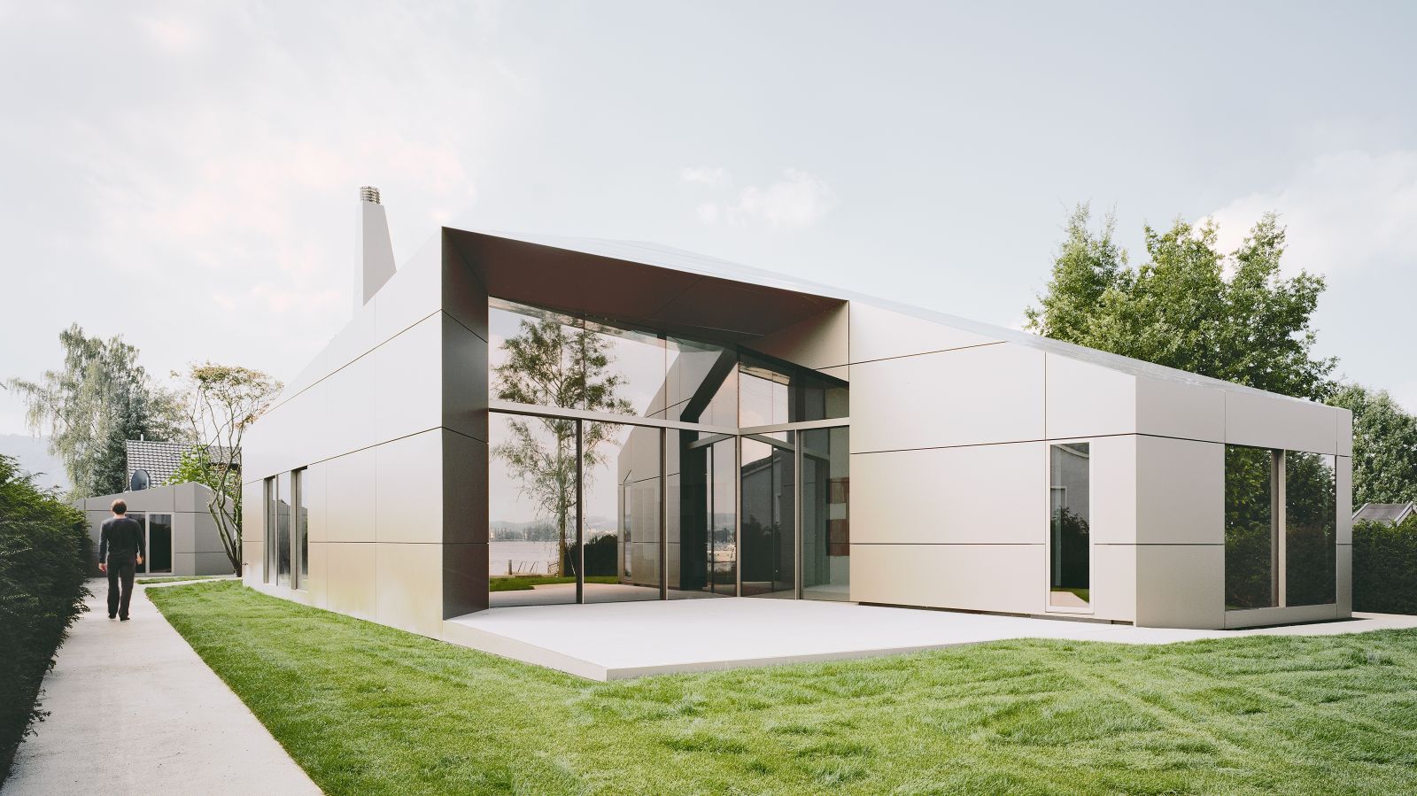 Die Fassade aus Aluminiumverbundplatten ist das Ergebnis eines sehr präzisen Arbeitsprozesses. Der Weg aus hell eingefärbtem Asphalt leitet den Besucher zum Eingang.