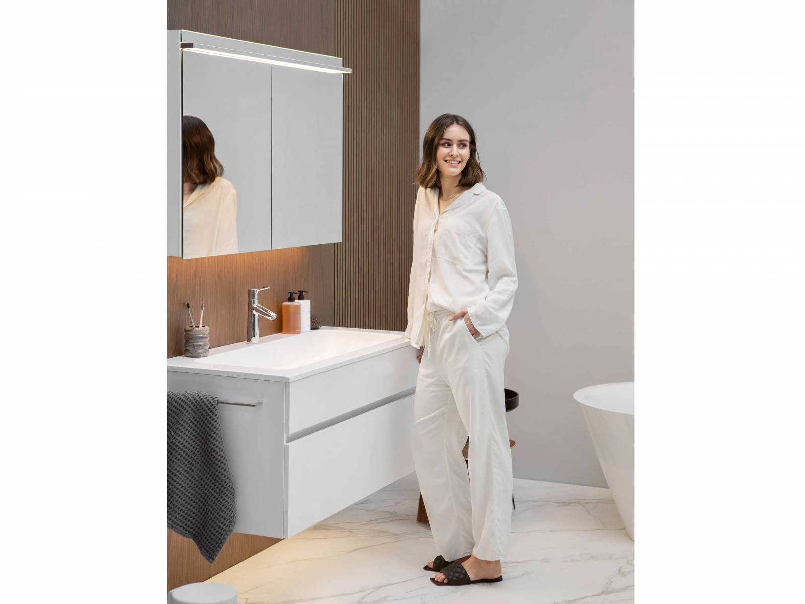Vor der Wandverkleidung aus Wallnussdekor macht sich das zeitlose Design des Waschtischs «Lima» besonders gut. Der zweitürige Spiegelschrank ist mit hochmoderner LED-Beleuchtungstechnologie ausgestattet. Sie sorgt dafür, dass das Bild im Spiegel perfekt reflektiert wird und der Raum optimal beleuchtet ist. DIPL. ING. FUST.