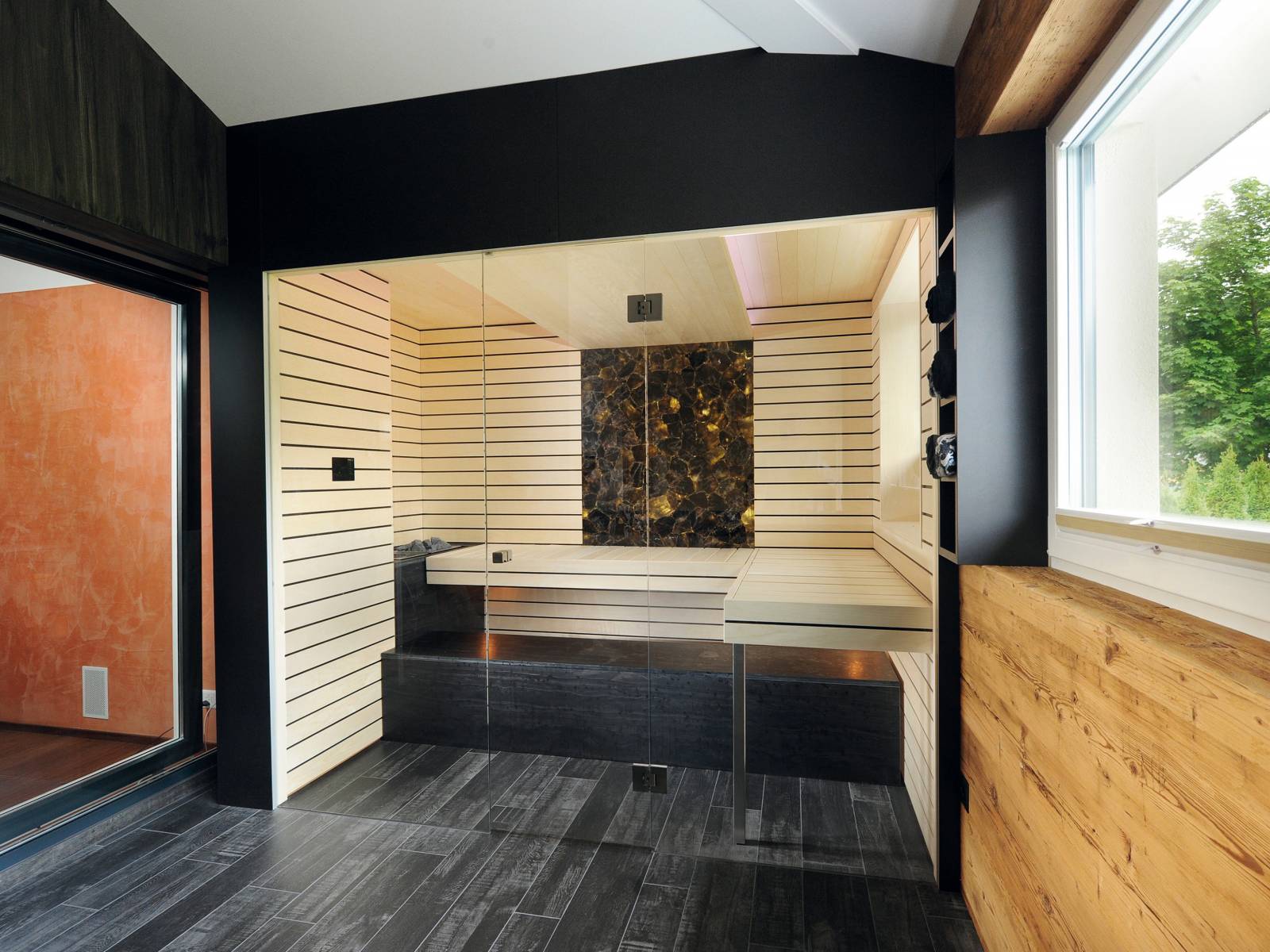 Der Saunabauer hat in diesem Beispiel aus einer Terrasse einen Wellnessbereich geschaffen. Hauptteil ist die Sauna aus heller Espen-Täfelung mit integriertem Biosa-Ofen. Verborgene Lichtquellen, bequeme Liegeflächen und ein hinterleuchteter Rauchquarz als Blickfang machen diesen Ort zu einer Wohlfühloase. Küng Sauna.