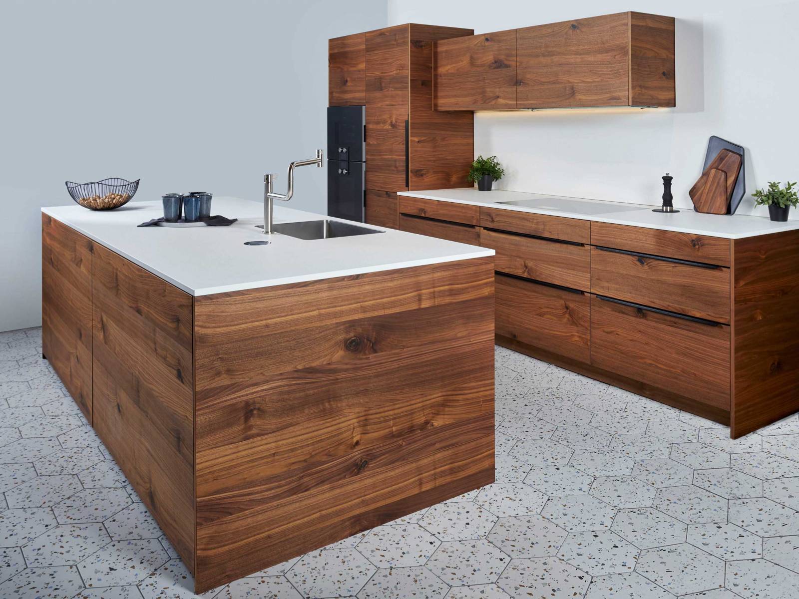 Holz in Verbindung mit der Farbe Weiss ist eine Kombination, die zeitlos und modern zugleich ist. Hier präsentiert sich die Küche in kräftigem Nussbaum mit weisser Arbeitsfläche, die durch den geschickt platzierten LED-Streifen optimal ausgeleuchtet wird. SABAG.