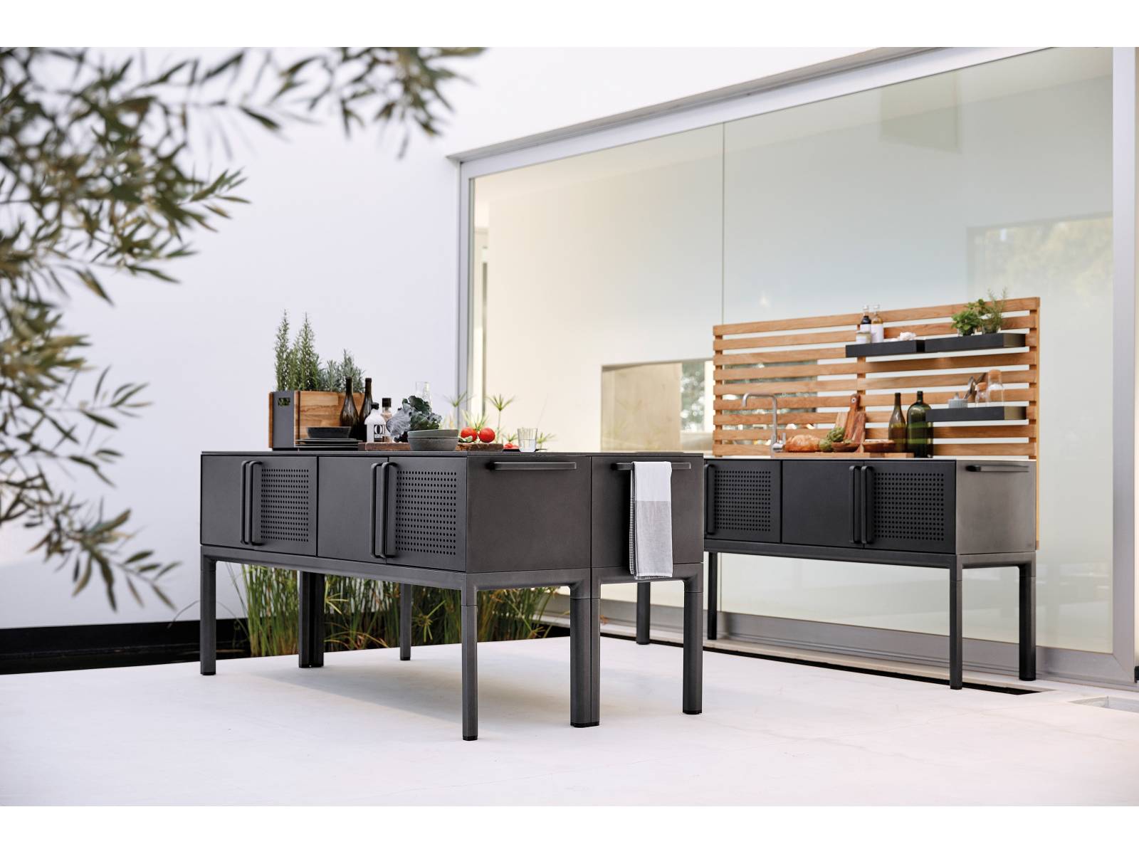 Das i-Tüpfelchen für die Sommersaison: Die modulbasierte Outdoor-Küche «Drop». Visuell so gestaltet, dass sie mit den Möbeln des Unternehmens, insbesondere den neuen Tischen der gleichnamigen Serie, harmoniert, wird sie aus Teakholz und Aluminium mit lavagrauer Pulverlackierung gefertigt. Tischplatte, Waschbecken und Mischbatterie sind aus Edelstahl. Cane-Line.