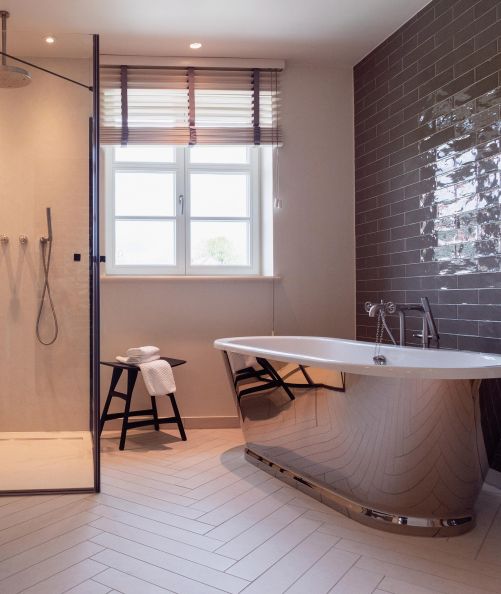 Hingucker im Badezimmer der Loge 6 ist die freistehende Badewanne mit silberfarbenem Finish. Nur gerade zwei dieser Wannen gibt es im Hotel. Hocker «Osso» von Ethnicraft.